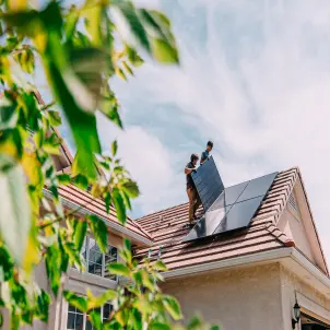 Junge Hausbesitzer installieren Solarmodule auf einem Wohnhaus