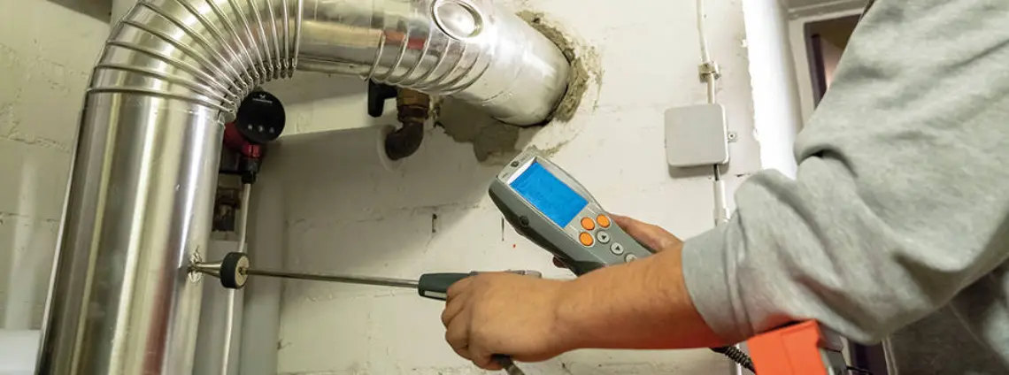 Ein Handwerker überprüft ein Heizrohr mit einem Messgerät