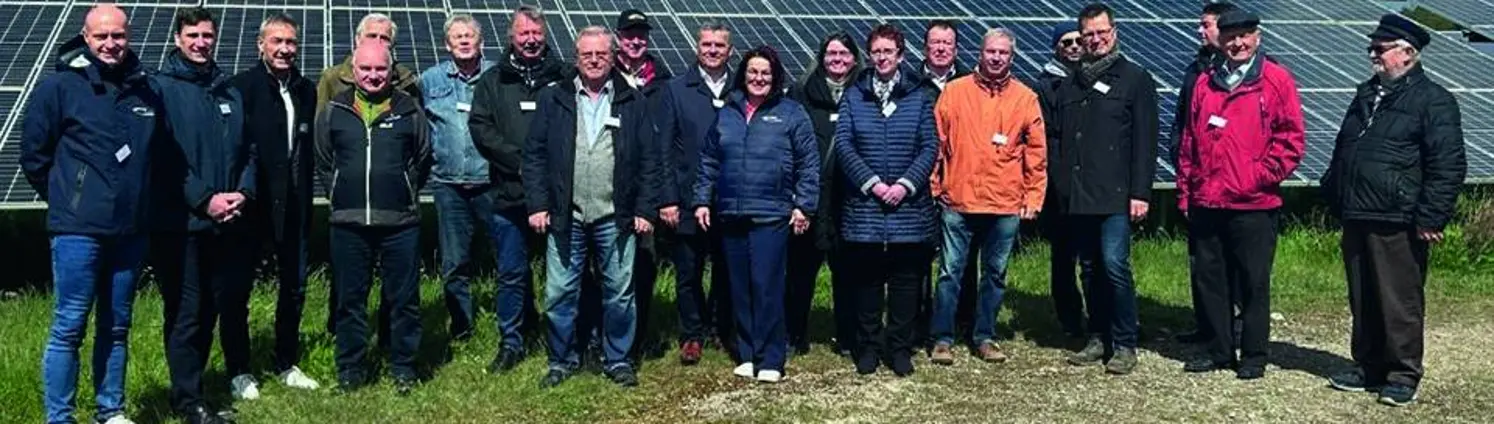 Mehrere Personen in Jacken stehen vor einem Solarpark